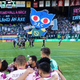 Portland Timbers MLS team huddles up before the match with Night in the Woods' Mae in the stands promoting Pride.